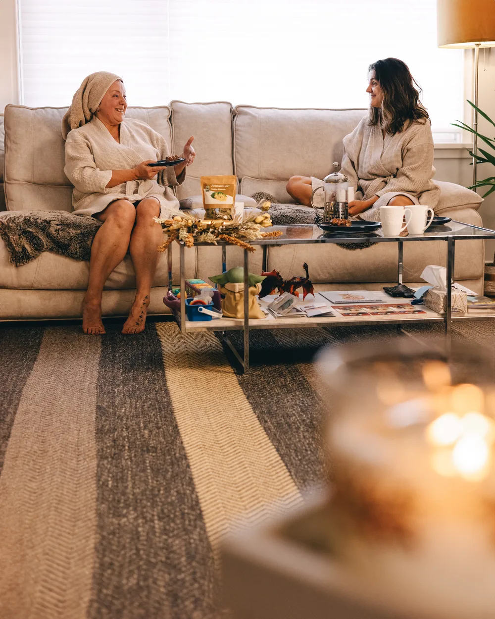 Two women talking while seated on a sofa in the Revive clinic lounge.