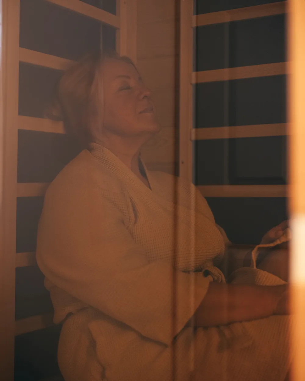 A client seated in a robe inside Revive’s wood-lined infrared sauna.