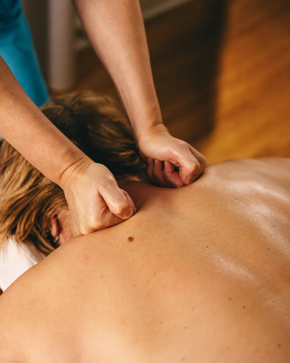 Close-up of a therapist applying hands-on pressure to a client’s upper back.
